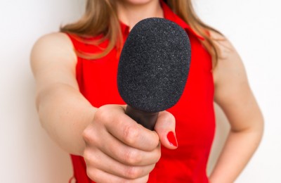 Female reporter with black microphone making interview - journalism and broadcasting concept