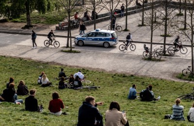 epa08367006 Police car on guard while people enjoy a sunny evening at the Wall Park (lit.: Mauerpark) in Berlin, Germany, 16 April 2020. Countries around the world are taking increased measures to stem the widespread of the SARS-CoV-2 coronavirus which causes the Covid-19 disease.  EPA/FILIP SINGER
