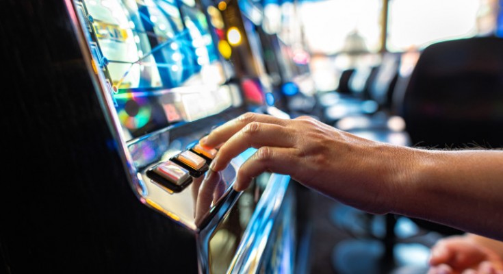 Closeup of Gambler Pressing the Spin Button While Playing Slot Machine in the Casino. Gambling Industry Theme.