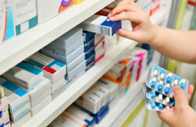 Pharmacist holding medicine box and capsule pack in pharmacy drugstore.