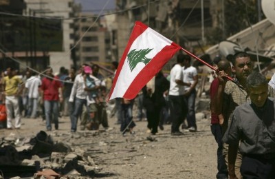 BEIRUT, LEBANON - AUGUST 14: Holding a Lebanese flag, Lebanese people returned to the southern suburbs to check on homes and businesses and to view the damage from Israeli air attacks to the area on August 14, 2006 in Beirut, Lebanon. After a U.N. brokered ceasefire came into effect between Israel and the militant group Hezbollah, Lebanese have been streaming south by the thousands.  (Photo by Spencer Platt/Getty Images)