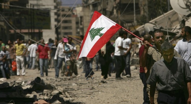 BEIRUT, LEBANON - AUGUST 14: Holding a Lebanese flag, Lebanese people returned to the southern suburbs to check on homes and businesses and to view the damage from Israeli air attacks to the area on August 14, 2006 in Beirut, Lebanon. After a U.N. brokered ceasefire came into effect between Israel and the militant group Hezbollah, Lebanese have been streaming south by the thousands.  (Photo by Spencer Platt/Getty Images)